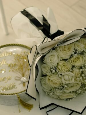 A beautiful white rose bouquet beside a decorative gift box, perfect for celebrations.