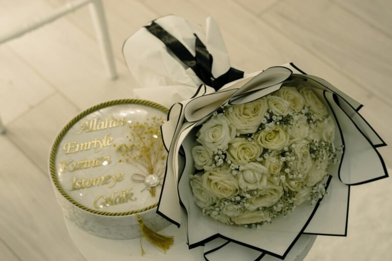 A beautiful white rose bouquet beside a decorative gift box, perfect for celebrations.