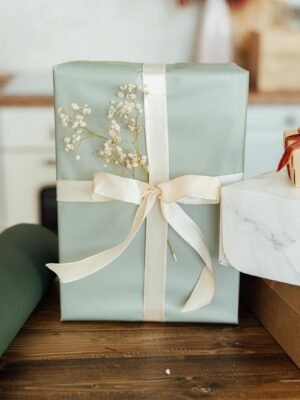 A beautifully wrapped gift with ribbon and Baby's Breath on a wooden table. Perfect for special occasions.