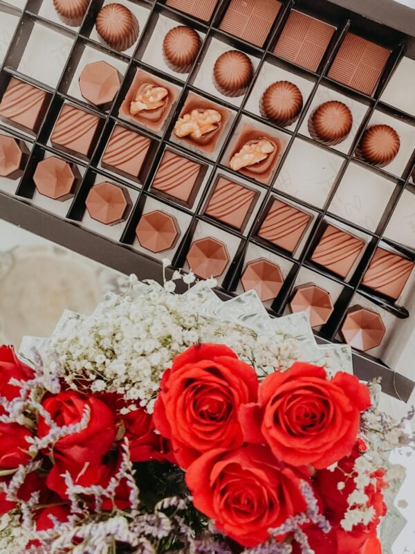 A box of assorted chocolates paired with vibrant red roses, perfect for special occasions.