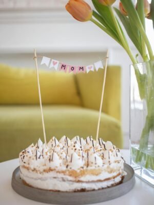 Delightful cake adorned with 'Mom' banner and vibrant tulips, perfect for Mother's Day celebration.