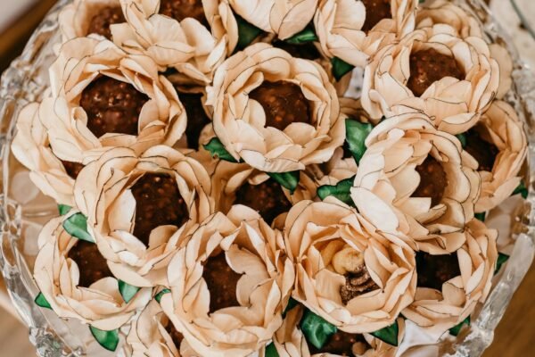 Top view of tasty chocolate balls in decorative paper flowers with wavy petals on plate during festive event